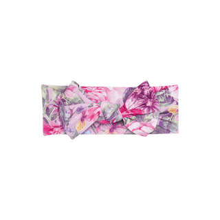 The Posh Peanut Bamboo Swaddle and Headwrap Set - Ellery (Floral) features a soft viscose bamboo headwrap with a large bow adorned with pink, purple, and yellow flowers on a green background.