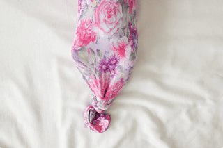 The Posh Peanut Bamboo Basic Knotted Gown - Ellery (Floral) showcases vibrant pink, purple, and gray floral patterns with roses on a white surface, featuring a colorful knot at the bottom.